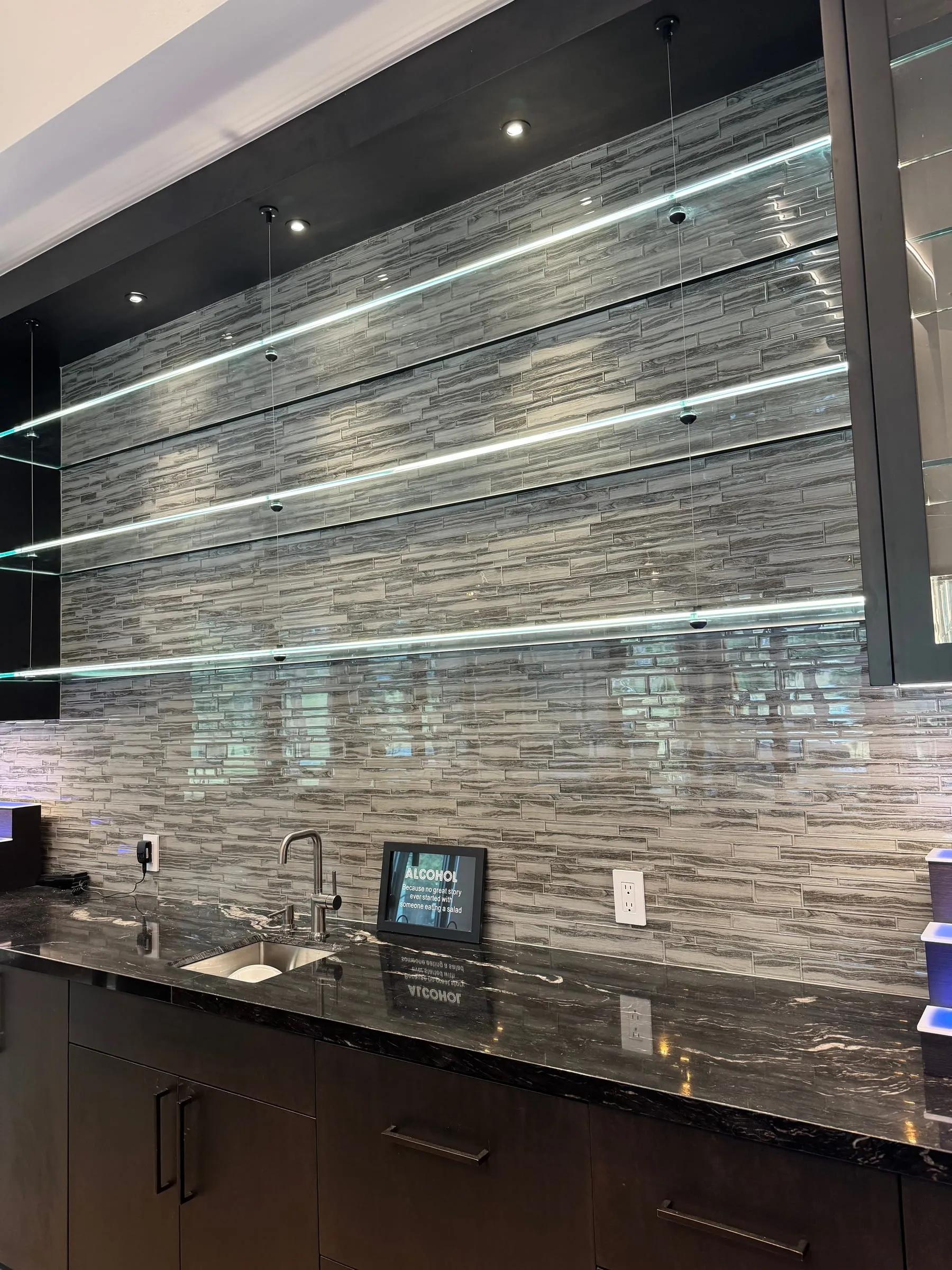 Floating backlit glass shelves on a stone home-bar wall