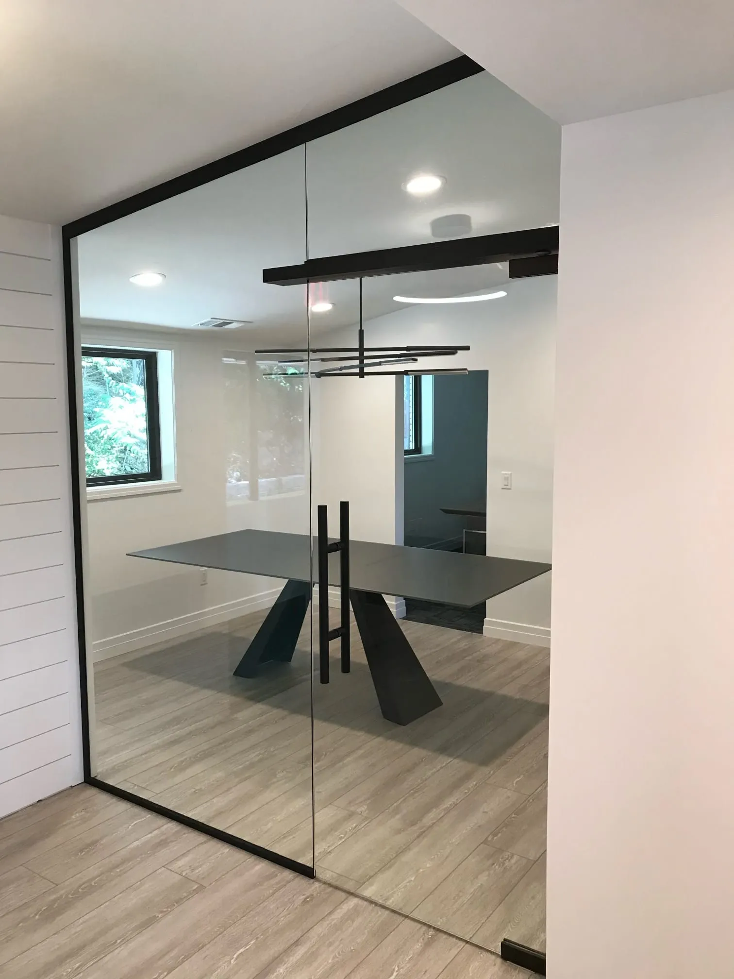 Black-frame glass wall and door around a dining area