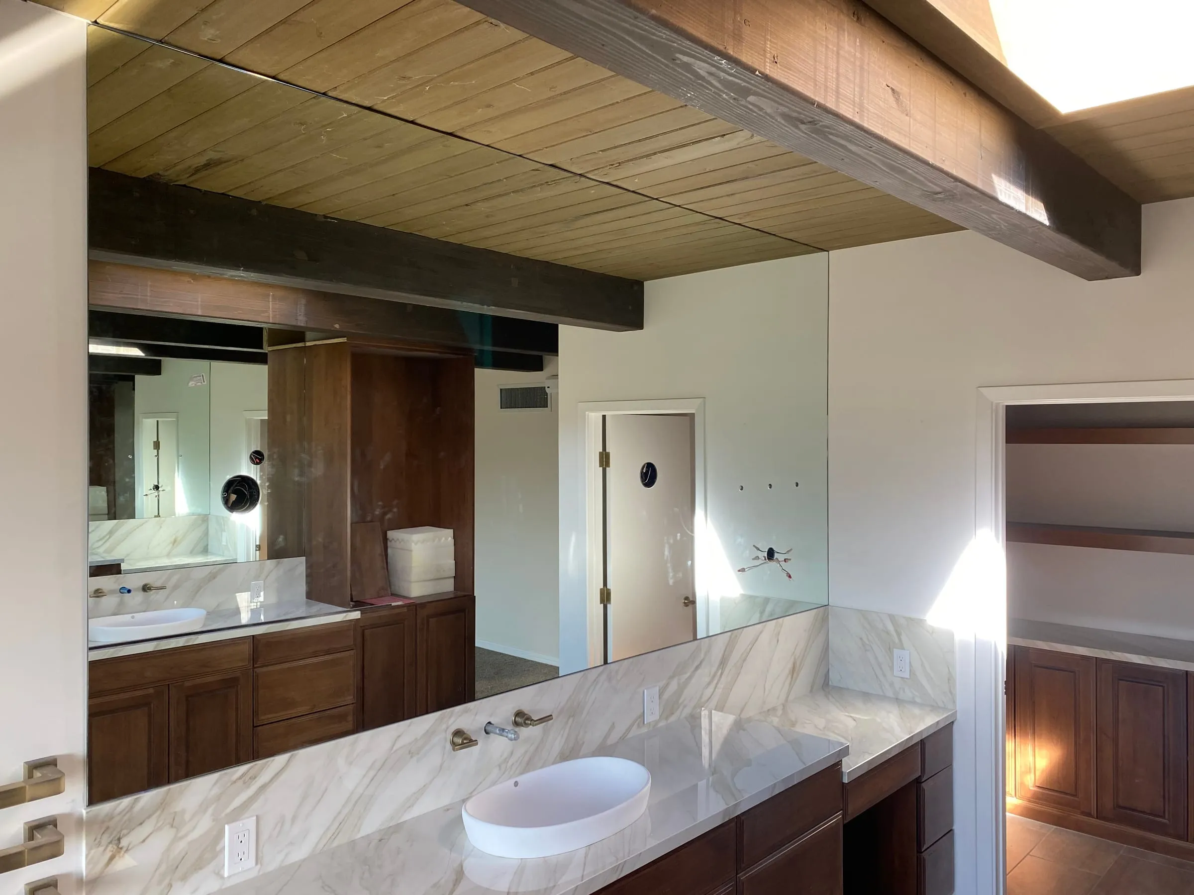 Custom vanity mirror in a bathroom with a wood plank ceiling