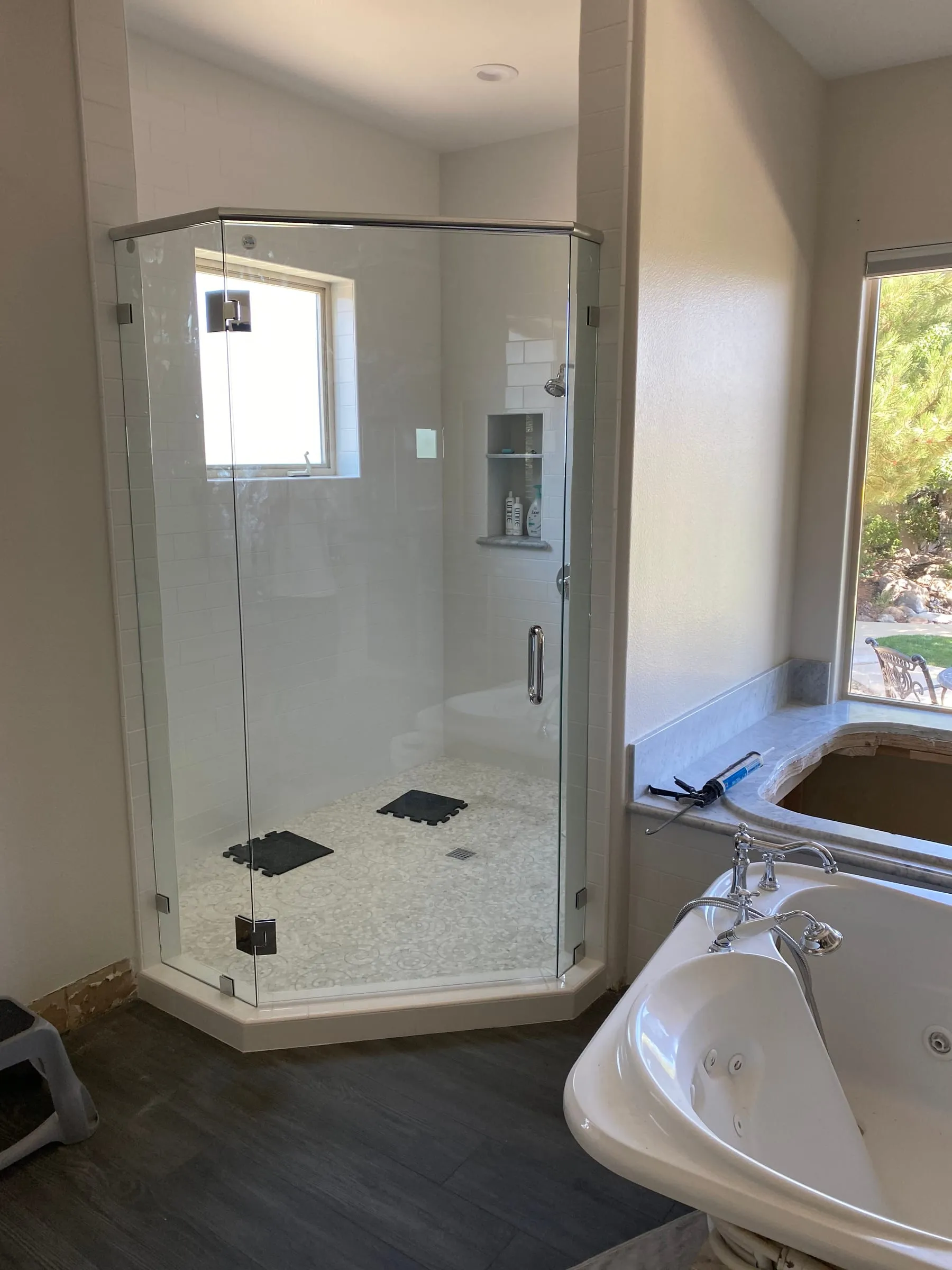 Neo-angle frameless corner shower beside a soaking tub